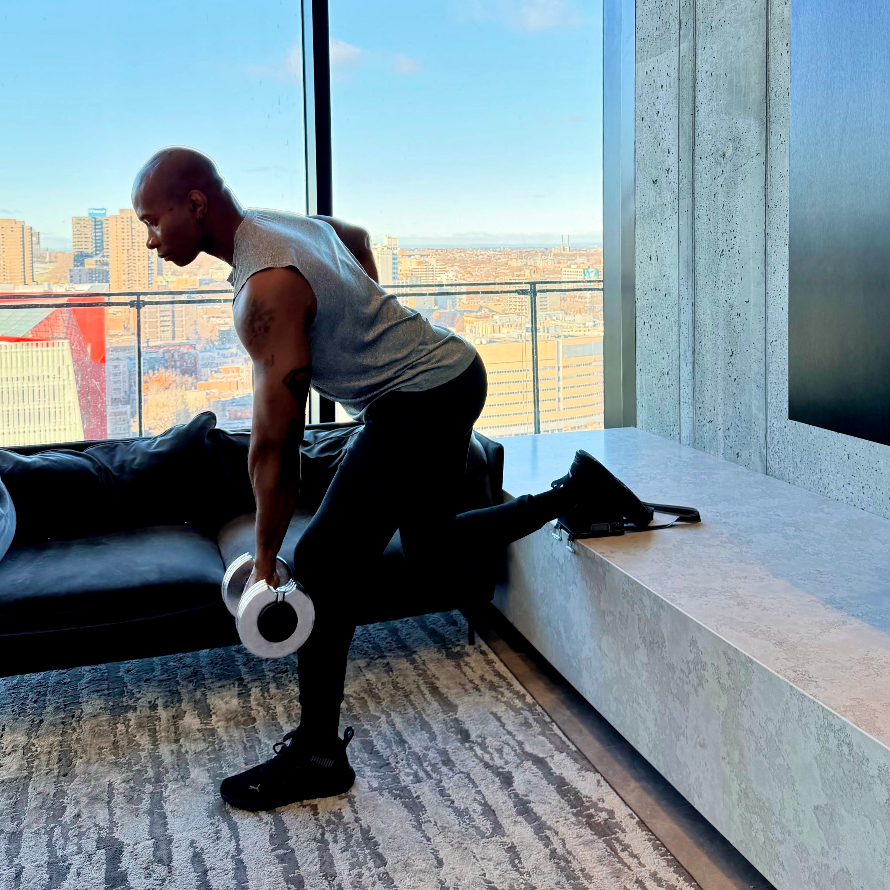 Person exercising with dumbbells in a modern living room with city view